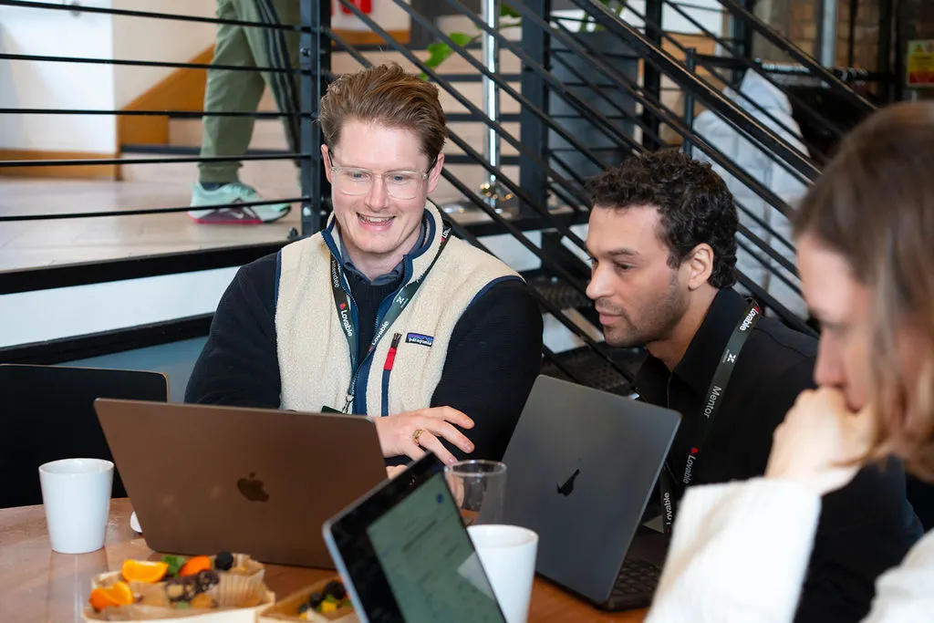 Workshop mentor helping participants at a laptop