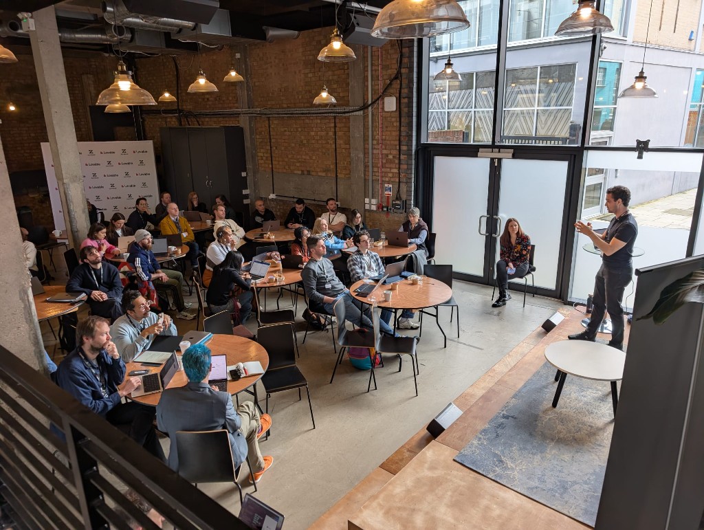 Wide view of workshop audience seated at round tables with laptops